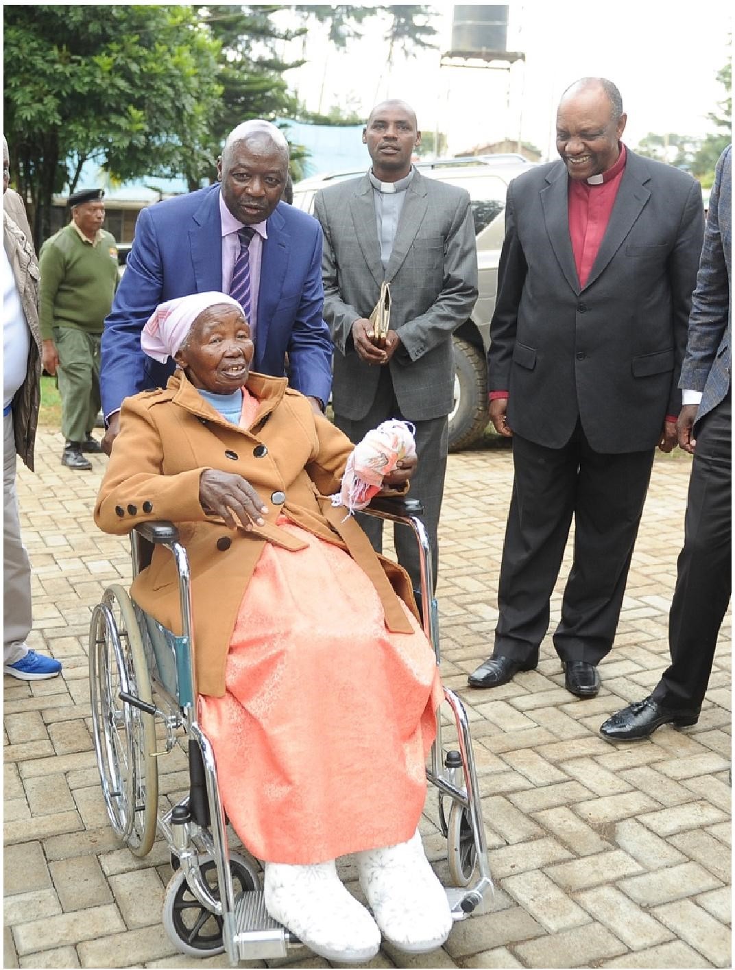 Photo Description: Dr Eng. Njoroge, the late Ruth Njoroge and clergy of the AIC Church